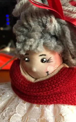 Muñeca de pelo gris con bufanda roja de punto